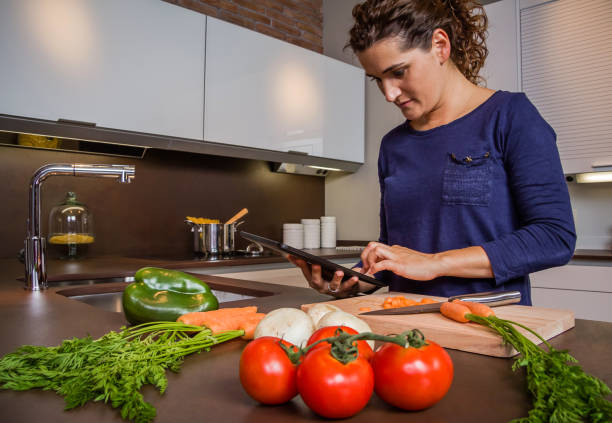 istock Girl in home kitchen looking recipe with a electronic tablet 1025005872