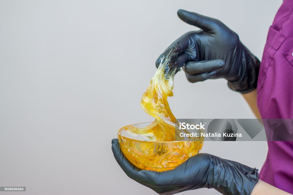 pâte de sucre ou de miel pour épilatoire avec mains gants noirs d’esthéticienne dans le salon spa - Epilation et concept de la beauté de la cire - Photo de Colle libre de droits