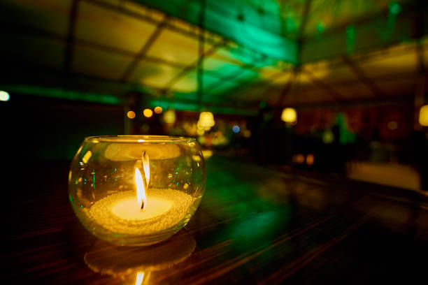 istock Glass candlestick with a burning candle close-up on a dark blurred background. 1025039418