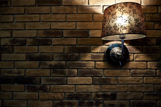 istock A glowing lamp on a dark brick wall. A background, a brick wall texture with a lamp. Copy space 1025039848
