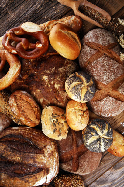 istock Different kinds of bread and bread rolls on board from above. Kitchen or bakery 1025047690
