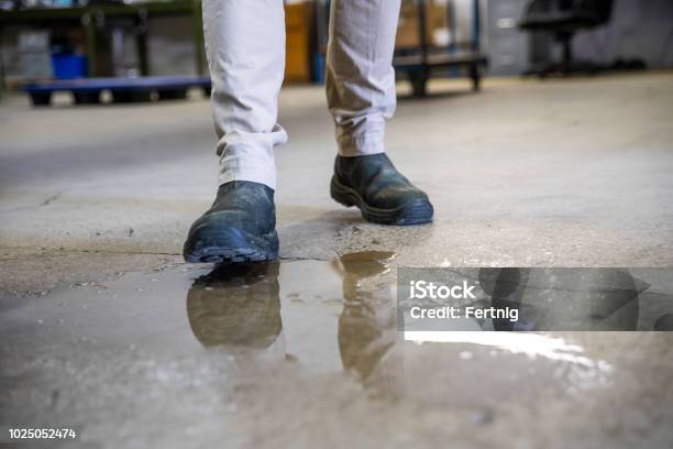 A Worker In A Warehouse Walking In Spilled Liquid Stock Photo - Download Image Now - Flooring, Danger, Falling