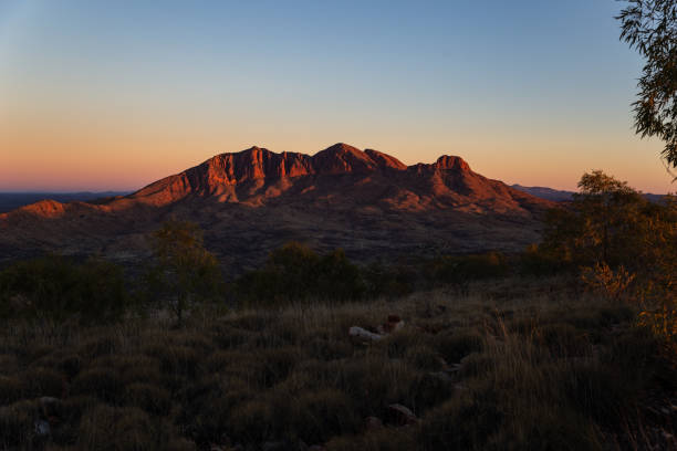 The early morning red light of a desert sunrise shine on Mount Sonder stock photo