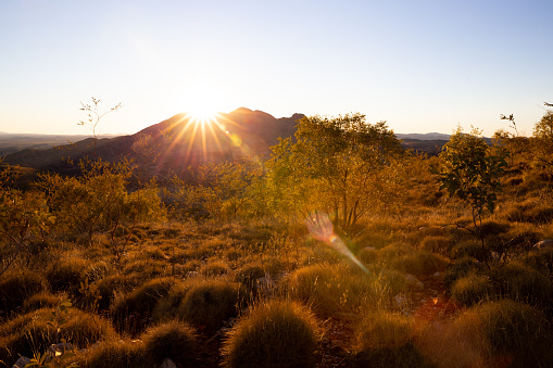 Late afternoon sun shines brightly across the top of a desert mountain in Australian Outback