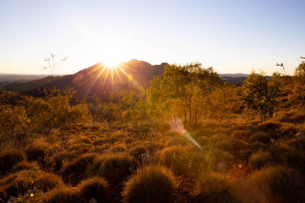Late afternoon sun shines brightly across the top of a desert mountain in Australian Outback stock photo