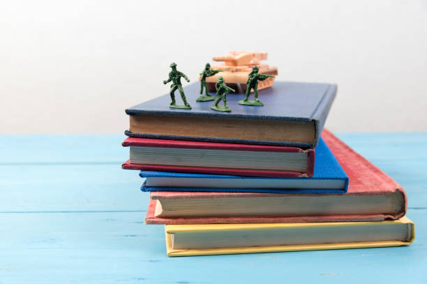 istock Stack Of Books With Figurines And Toy Armored Tank On Table 1025081988