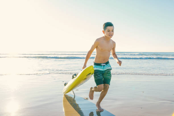 ビーチ サーフィン レスキュー ボードでオーストラリアのアボリジニの少年 - gold coast australia lifeguard sea ストックフォトと画像