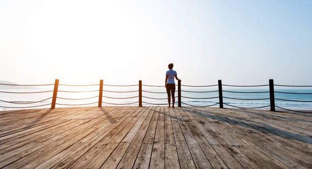 istock Woman standing on boardwalk at the beach 1025092672