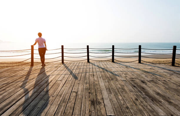 Woman standing on boardwalk at the beach.