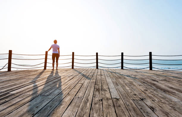 istock Woman standing on boardwalk at the beach 1025095074