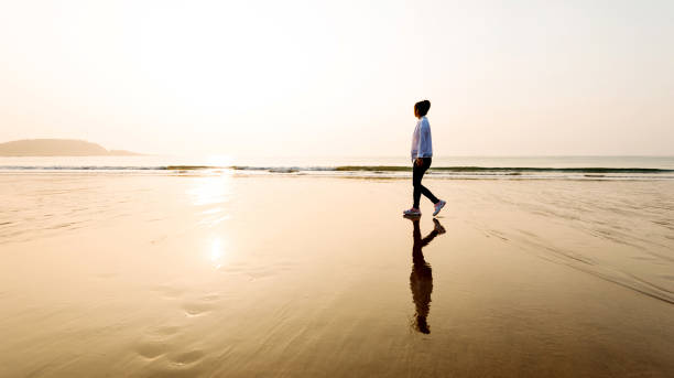 istock Woman walking on the beach at sunset 1025097754