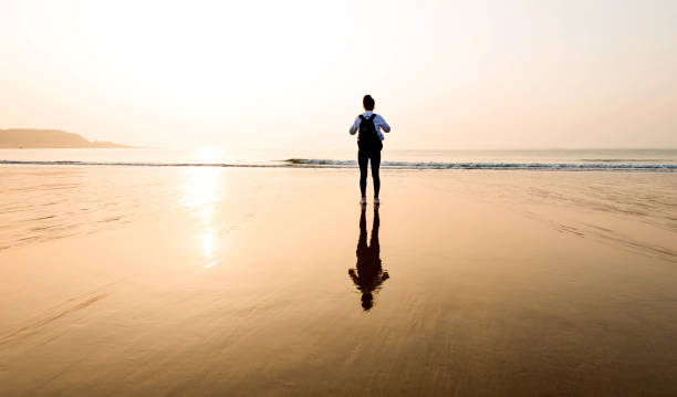 istock Woman backpacker standing on the beach at sunset 1025098154