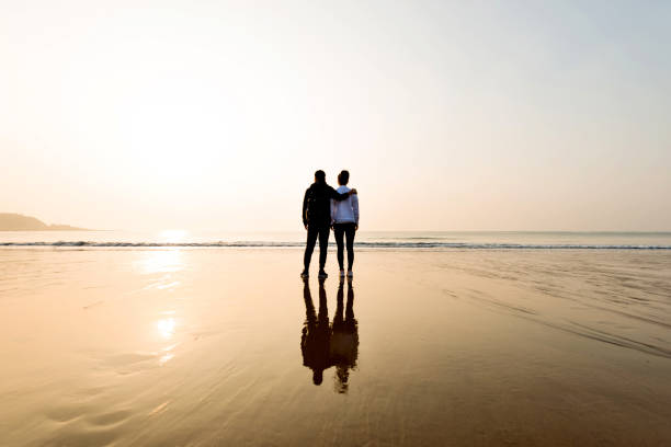 istock Couple standing at beach with arm around 1025103302