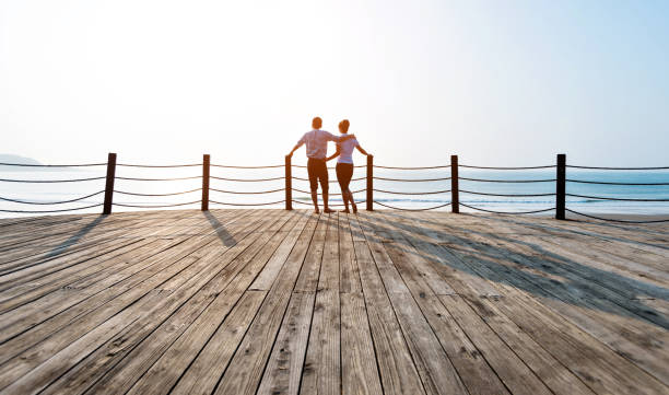 istock Couple standing on boardwalk at the beach 1025103526