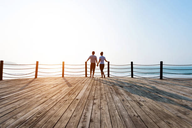istock Couple standing on boardwalk at the beach 1025103736