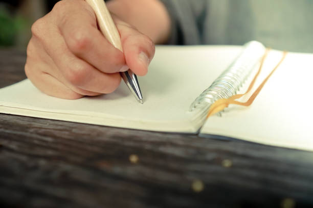 istock Copy space of woman hand writing down in white notebook with sun light background. 1025141918