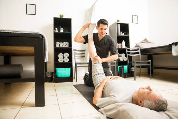 istock Doctor Assisting Elderly Patient With Leg Exercise In Clinic 1025144720