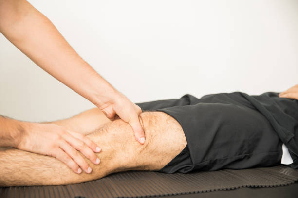 istock Physiotherapist Applying Pressure To Massage Young Man's Knee 1025145978