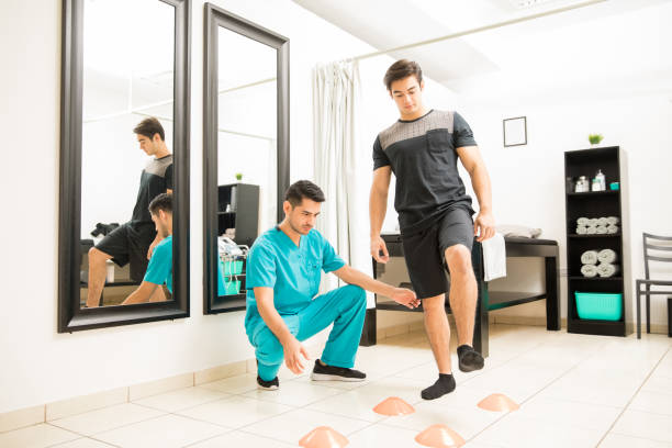Therapist Motivating Male Patient To Walk Between Cones
