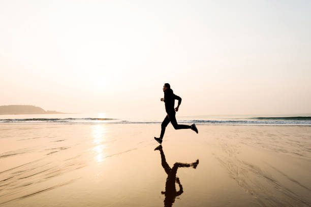 istock Man running on the beach at sunset 1025155000