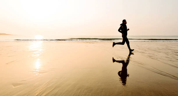 istock Man running on the beach at sunset 1025157624