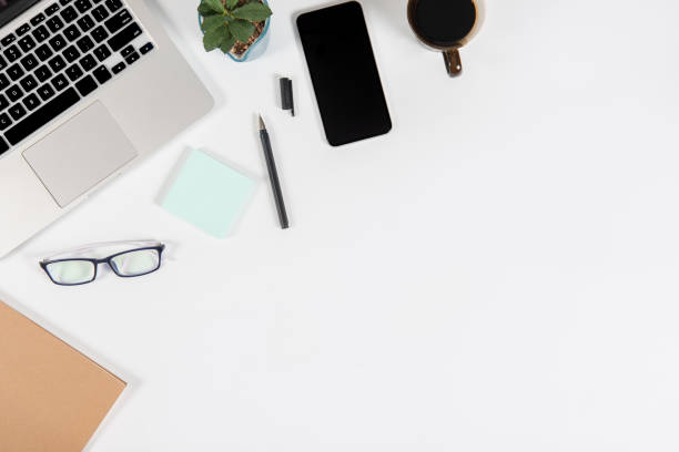 istock Office table with laptop computer, smartphone, pen, notebook and coffee on isolated pure white background / Laptop and tablet mockup concept. (Selective Focus) 1025207578