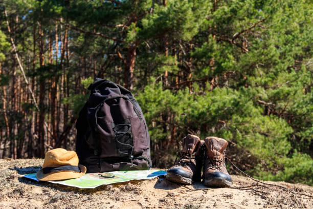 istock Tourist backpack with hiking boots, hat, compass and map on the glade in pine forest 1025207822