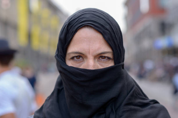 mujer musulmana con un hiyab negro en la ciudad - women middle aging process covering fotografías e imágenes de stock