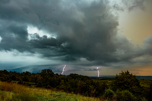 Bolts of lightning during a summer evening thunderstorm over a mid-western field.