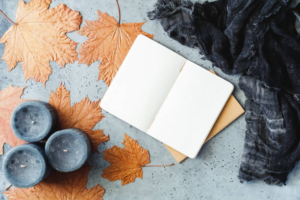 istock Autumn flat lay composition on a grey concrete background. Maple leaves, the open notebook with empty sheets, black aromatic candles and warm scarf. Mockup, top view. 1025234794