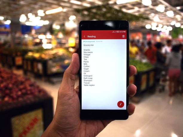 Hand holding a smartphone with grocery list stock photo