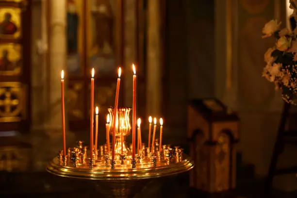 Photo of Orthodox Church candles with icons, the Bible and the cross