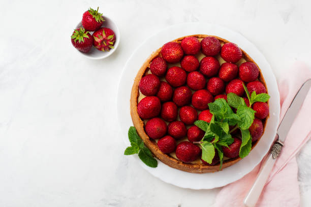 istock Cheesecake with fresh strawberries and mint on white plate on gray concrete background. Top view. 1025251794