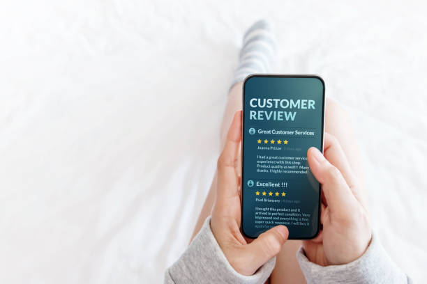 concetto di customer experience. donna sdraiata a letto per leggere la recensione online tramite smartphone prima di acquistare prodotti e servizi, feedback più positivo sullo schermo mobile - smart phone writing assistance business foto e immagini stock