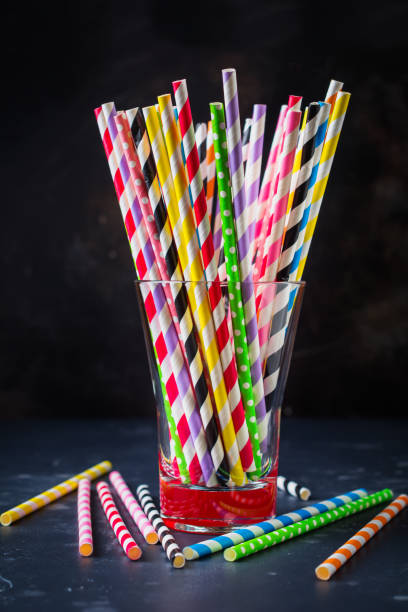 istock Multicolored paper rolls for cocktail or straws in glass jar on dark background. Selective focus. 1025291856