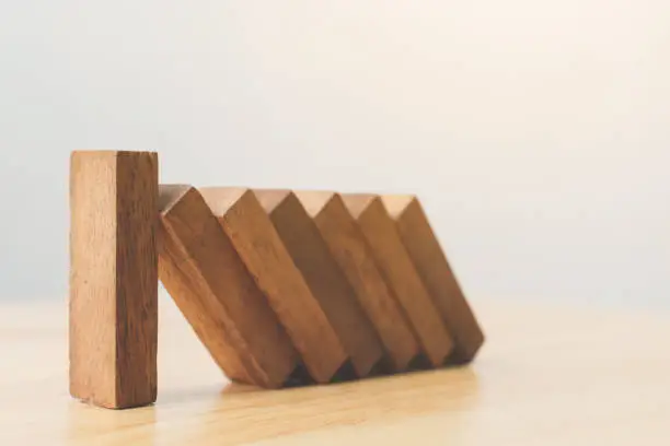 Photo of Business risk management concepts. Wooden block stop falling of other pieces of domino effect.