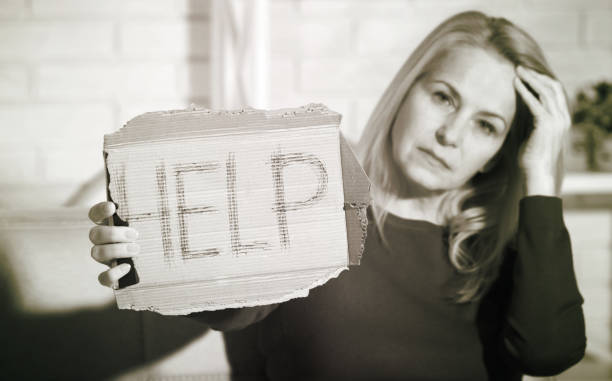 istock Woman alcoholic social problems concept sitting asking for help. Middle aged woman holding a sign m asking for help. 1025335280