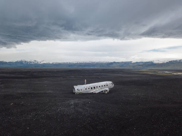 istock DRONE view Young woman stands on airplane crashed on black sand beach looking around her contemplating surroundings 1025336252