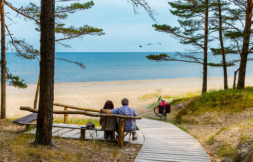 Happy couple of tourists are resting near a sandy beach of the Baltic Sea