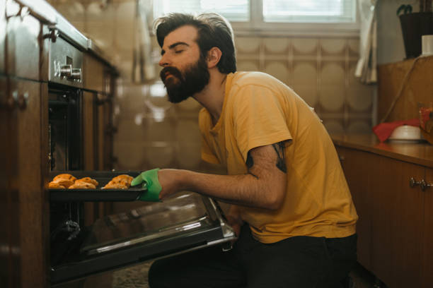 istock Handsome man taking out freshly baked pastries from the oven 1025370076