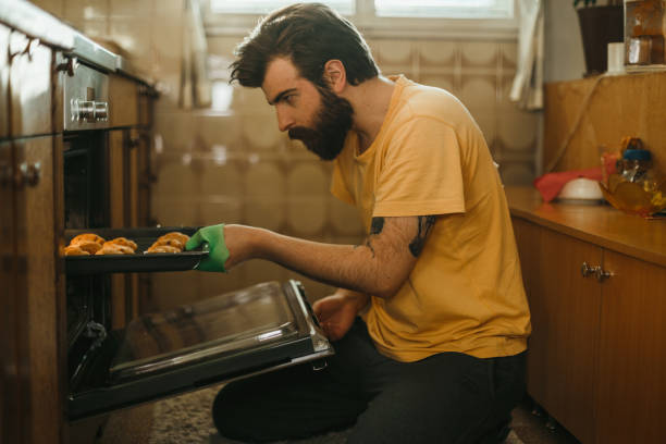 istock Handsome man taking out freshly baked pastries from the oven 1025370096