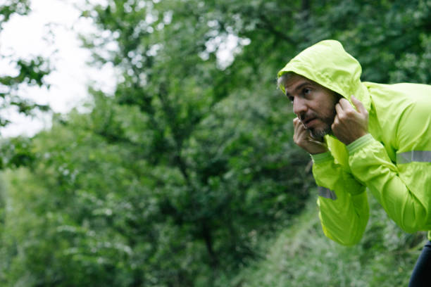 Portrait of a mid adult man exercising outdoors on a road in the early morning, in rainy weather.