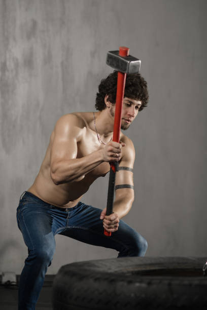 istock Athletic man hits tire - workout at gym with hammer 1025391106