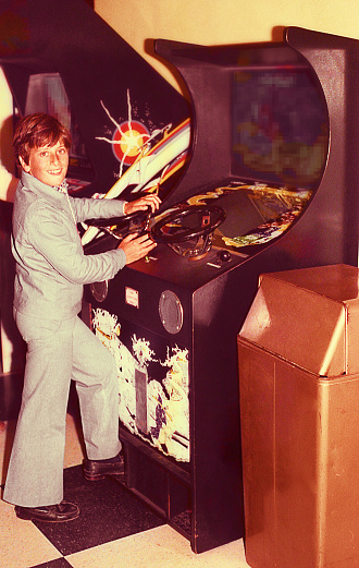 Vintage image of a boy playing in an old vide ogame machine.