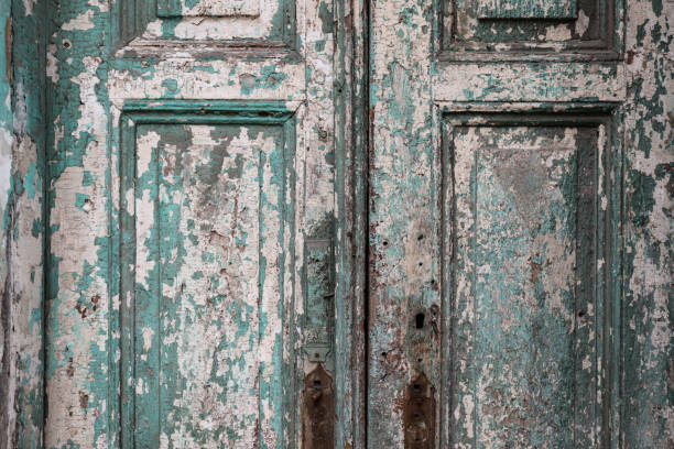 Old worn wooden entrance door with flaking paint as grunge texture and background