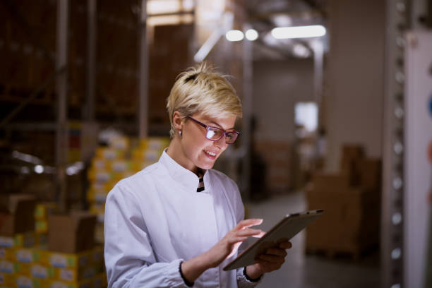 young female manager is using tablet in storage room of a factory. - dutch ethnicity imagens e fotografias de stock