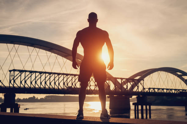 istock Fitness training outdoors. Handsome man working exercises in early morning with sunrise. Muscular man training outside. Sunny fitness morning. 1025413872