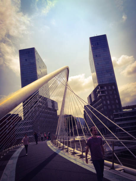 Bilbao, Spain - June 26, 2014: People walking along the Zubizuri footbridge in Bilbao city, one of the many bridges designed by Santiago Calatrava all over the world
