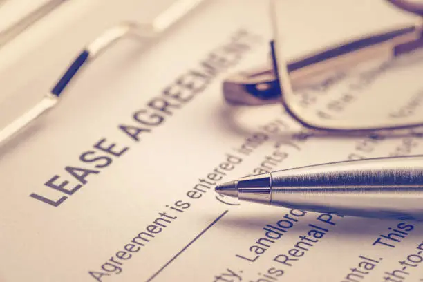 Photo of Business legal document concept : Pen and glasses on a lease agreement form. Lease agreement is a contract between a lessor and a lessee that allow lessee rights to use of a property owned by lessor