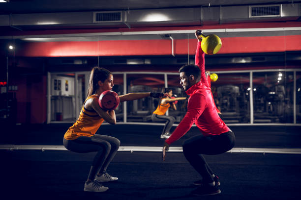 cerca de una forma pareja motivada hacer ejercicio en un gimnasio con la campana de la caldera. - secrecy instructor exercising individuality fotografías e imágenes de stock